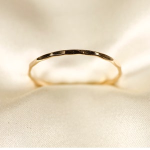 May include: A thin gold band ring with a hammered texture.