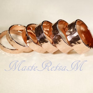 May include: Five rose gold hammered metal rings stacked on top of each other.