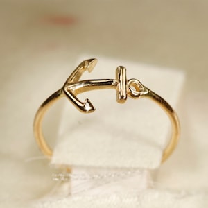 May include: A gold anchor ring. The anchor is a simple design with a small loop at the top.