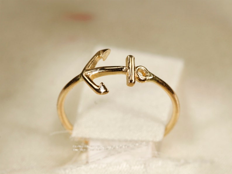 May include: A gold anchor ring. The anchor is a simple design with a small loop at the top.