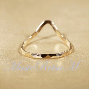 May include: A gold-toned ring with a unique, open, triangular design. The ring has a hammered texture.