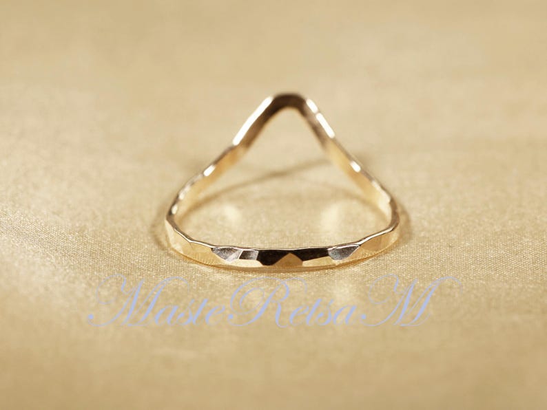 May include: A gold-toned ring with a unique, open, triangular design. The ring has a hammered texture.