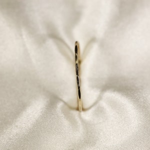 May include: A thin gold ring with a hammered texture.