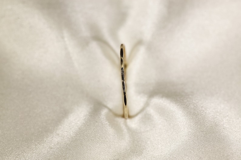 May include: A thin gold ring with a hammered texture.