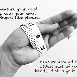 May include: A black and white image showing how to measure your wrist size. A hand is holding a tape measure around the wrist. The text reads: "To measure your wrist size, hold your hand and fingers like picture. Measure around the widest part of your hand, that is your size."