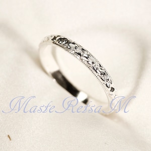 Puede incluir: Un fino anillo de banda de plata con un delicado diseño floral grabado alrededor de toda la banda.