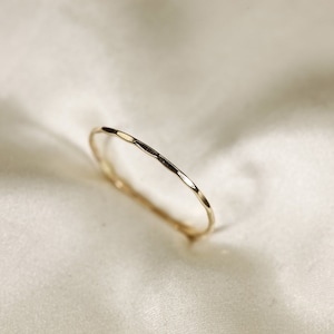 May include: A thin gold band ring with a hammered texture.