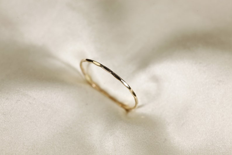 May include: A thin gold band ring with a hammered texture.