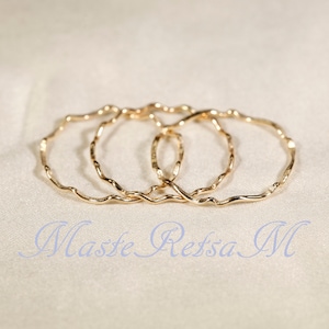 May include: Three gold-toned, wavy, metal rings stacked on top of each other.