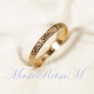 Puede incluir: Un fino anillo de banda de oro con un delicado diseño floral grabado alrededor de toda la banda.
