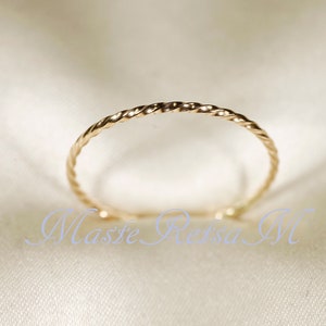 May include: A thin gold ring with a twisted design.