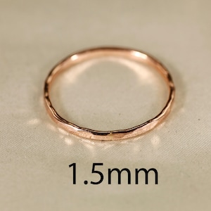 May include: A simple, hammered rose gold band ring with a 1.5 mm width. The ring is smooth and has a slightly textured finish.