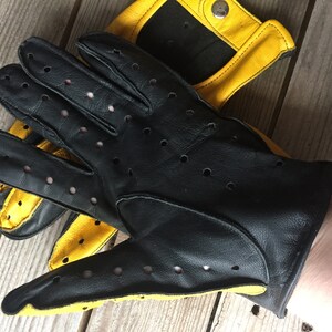 May include: Black leather driving gloves with yellow accents and perforated detailing.