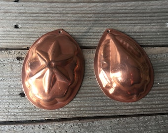 Puede incluir: Dos moldes para pasteles de cobre vintage. Un molde tiene forma de estrella y el otro tiene forma de pera.