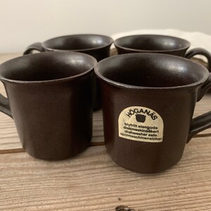 Puede incluir: Cuatro tazas de cer&aacute;mica marr&oacute;n con una etiqueta blanca que dice "H&Ouml;GAN&Auml;S blyfritt stengods diskmaskins&auml;kert dishwasher safe sp&uuml;lmaschinenischer".