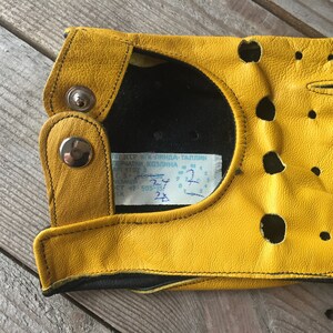 May include: Yellow leather driving gloves with black stitching and a label that reads "K.I.N.D.L.A - TALLINN".