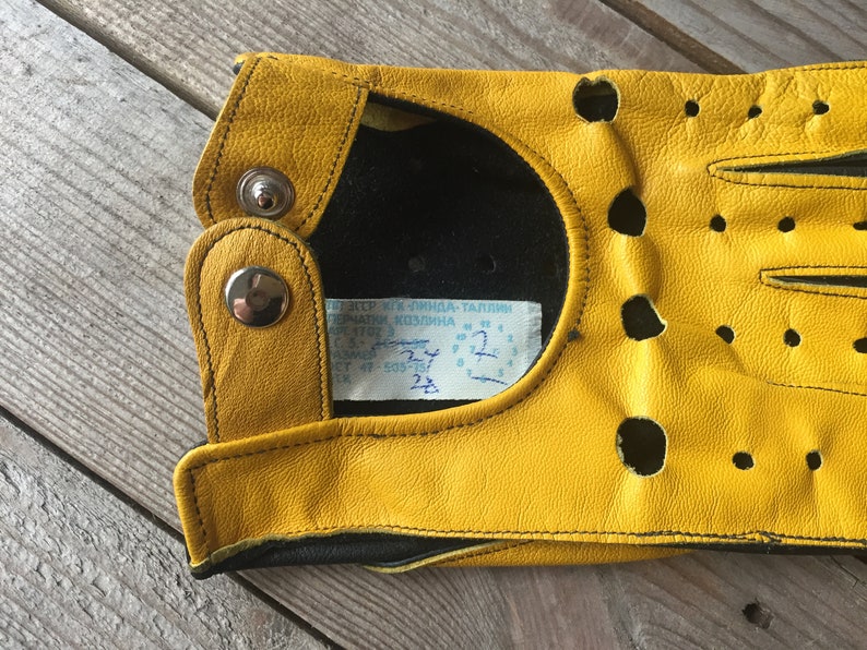 May include: Yellow leather driving gloves with black stitching and a label that reads "K.I.N.D.L.A - TALLINN".