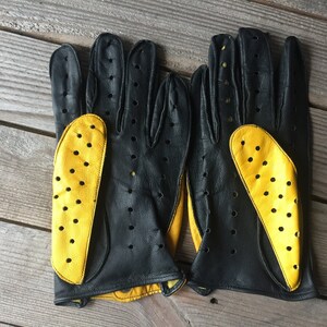 May include: A pair of black leather driving gloves with yellow perforated leather accents.