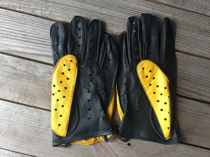 May include: A pair of black leather driving gloves with yellow perforated leather accents.