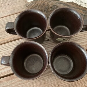 Puede incluir: Cuatro tazas de cer&aacute;mica marrones con un esmalte marr&oacute;n oscuro. Las tazas tienen una forma redondeada y un asa en el lateral.