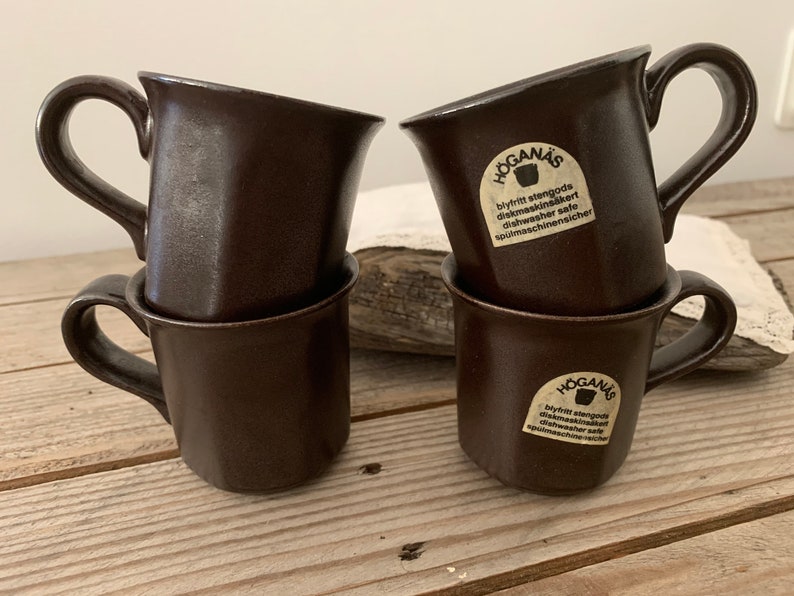Puede incluir: Cuatro tazas de cer&aacute;mica marr&oacute;n con una etiqueta blanca que dice "Hogan&auml;s Blyfritt stengods diskmaskinss&auml;kert Dishwasher safe Sp&uuml;lmaschinenicher".