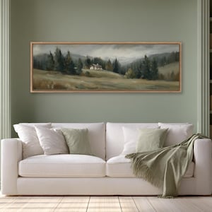 May include: A panoramic landscape painting in a wooden frame featuring a small cabin nestled in a grassy field surrounded by dark green pine trees under a cloudy, overcast sky. The artwork displays muted earth tones and soft, painterly brushstrokes.