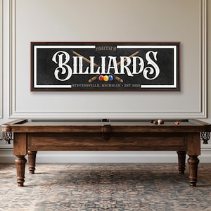 May include: A rectangular wall sign with a dark textured background featuring the text SMITH'S BILLIARDS, STEVENSVILLE, MICHIGAN, EST 2026. The design includes two crossed wooden pool cues and three colorful billiard balls in red, yellow, and blue.