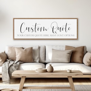 May include: A rectangular wall sign with a light wood frame featuring the text "Custom Quote" in a large black script font above the smaller sans-serif text "YOUR CUSTOM QUOTE HERE, MANY FONT OPTIONS" on a white background.