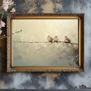 May include: A framed painting of three brown sparrows perched on a branch. The background is a soft, muted green and brown with a hazy, atmospheric effect. The frame is gold with ornate details.