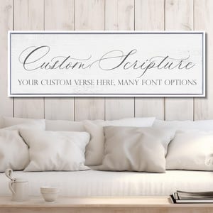 May include: A rectangular white wooden sign with a thin dark frame. The text "Custom Scripture" is written in a large, elegant cursive font, followed by the text "YOUR CUSTOM VERSE HERE, MANY FONT OPTIONS" in a smaller, clean sans-serif font.