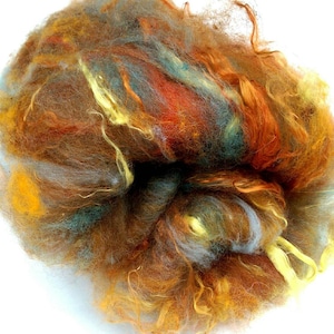 May include: A clump of colourful wool fibre in shades of brown, orange, yellow, blue, and grey. The fibre is soft and fluffy, and it would be perfect for spinning or felting.