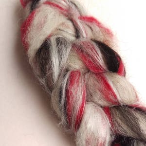 May include: A braided strand of yarn in red, white, and black colors. The yarn is soft and fluffy, and it is perfect for knitting or crocheting.