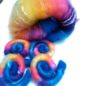 May include: A colourful ball of yarn with a rainbow of colours, including yellow, orange, pink, purple, and blue. The yarn is arranged in a spiral shape, creating a visually appealing design.