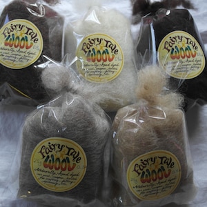 May include: Five bags of Fairy Tale Wool, each containing a different colour of wool. The colours are brown, white, light brown, grey, and beige. Each bag has a label with the words "Fairy Tale Wool" and "Naturally hand dyed".