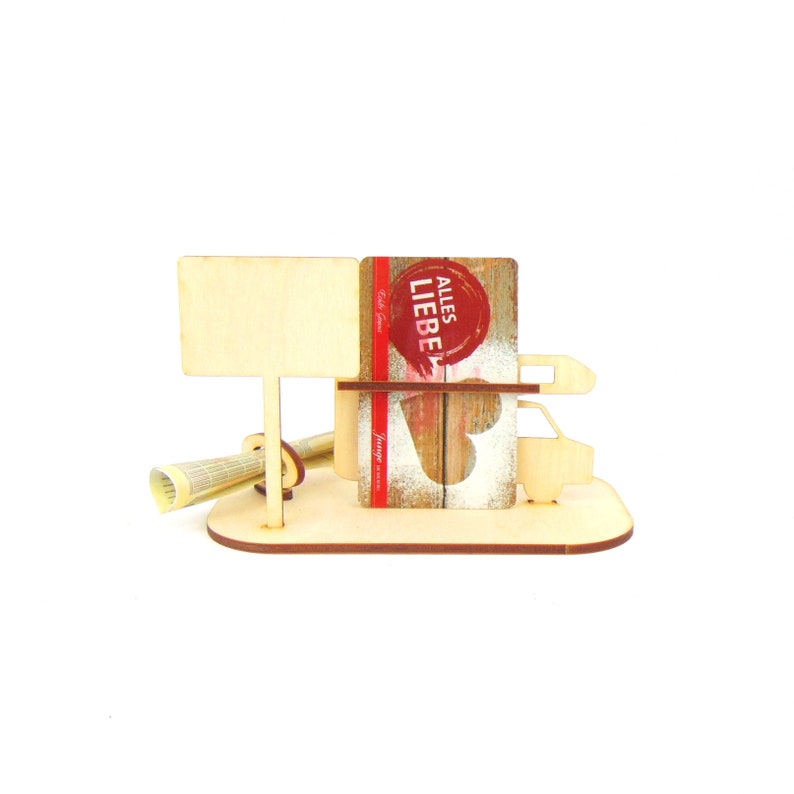 May include: Wooden stand with a small wooden car, a sign, and a gift card that says "Alles Liebe".
