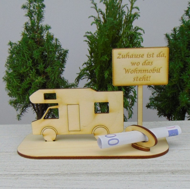 May include: A wooden cutout of a camper van with a sign that reads "Zuhause ist da, wo das Wohnmobil steht!"  The camper van is holding a rolled up bill of money.