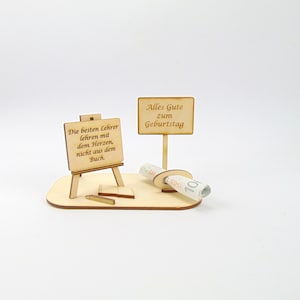 Könnte beinhalten: Ein Geschenkset zur Lehreranerkennung aus Holz. Es enthält eine Miniaturstaffelei mit Text, ein Schild mit der Aufschrift "Alles Gute zum Geburtstag", einen aufgerollten Gegenstand, einen Bleistift und ein kleines Buch. Das Set ist aus hellem Holz.