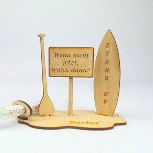 May include: Wooden stand up paddle board and paddle with a sign that reads "Wenn nicht jetzt, wann dann?" and the name "B&auml;rbel" engraved on the base.