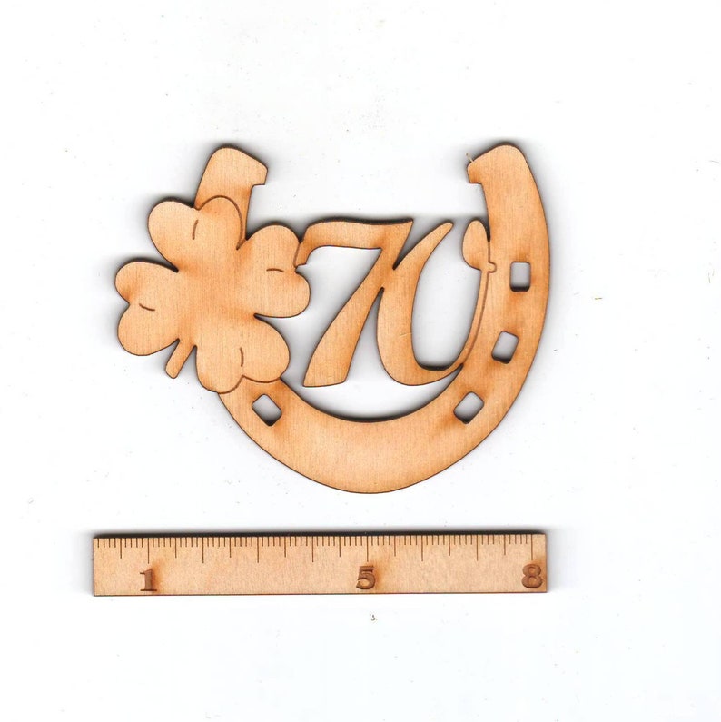 May include: Wooden horseshoe cutout with a four-leaf clover and the number 70. The horseshoe is approximately 3 inches wide.