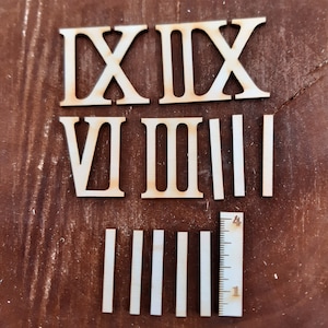 Könnte beinhalten: Ein Satz aus Holz-Römischen Ziffern für eine Uhr, einschließlich der Zahlen I, II, III, V, VI, VII, VIII, IX, X, XI, XII, XIII, XIV, XV, XVI, XVII, XVIII, XIX und XX. Die Zahlen sind aus unbehandeltem Holz und können bemalt oder gebeizt werden.