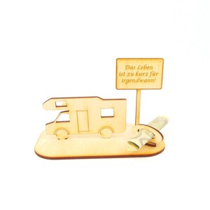 May include: Wooden camper van money holder with a sign that reads "Das Leben ist zu kurz f&uuml;r irgendwann!"  The sign is attached to a wooden post. A rolled up bill of money is placed in the slot on the camper van.