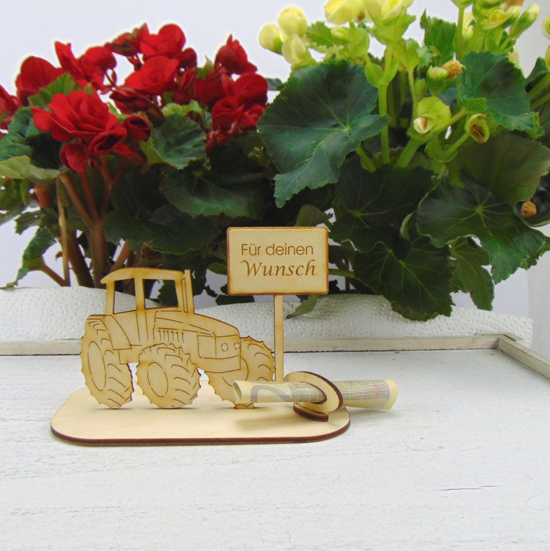 May include: Wooden tractor money holder with a sign that reads "For your wish". The tractor is brown and has a rolled up bill of money in the back.