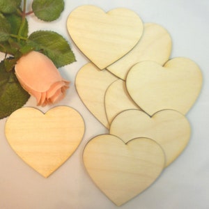 May include: A set of eight unfinished wooden heart shapes. The hearts are arranged in a cluster, with a single heart in the foreground. The hearts are a light brown color and have a smooth surface.