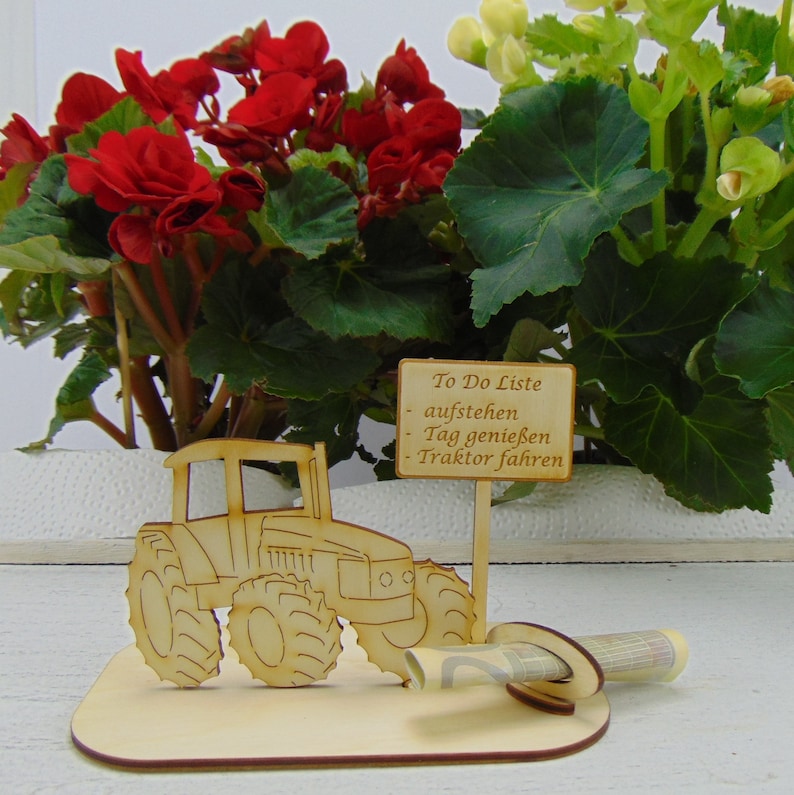 May include: Wooden tractor figurine with a sign that reads "To Do Liste - aufstehen - Tag geniessen - Traktor fahren". The figurine is on a wooden base with a rolled up bill of money.