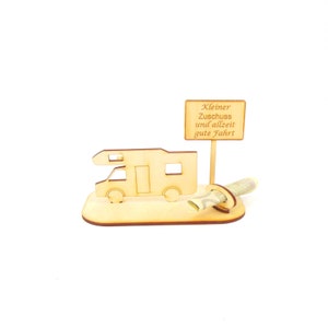 May include: Wooden camper van money holder with a sign that reads "Kleiner Zuschuss und allzeit gute Fahrt" which translates to "Small contribution and always good journey".