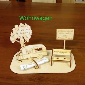 May include: A wooden model of a camper van, a tree, a bench, and a sign with the text "Tr&auml;ume nicht dein Leben Lebe deinen Traum" and "Lieblingsplatz". The model is on a wooden base.