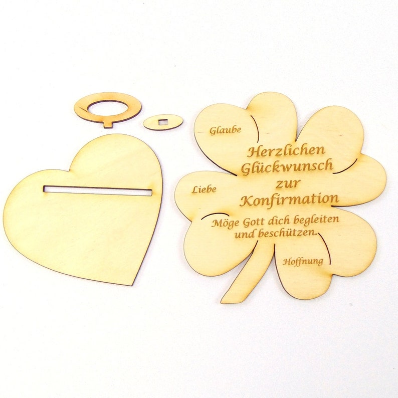 Op de afbeelding: Houten knutselset voor een bevestigingsviering. De set bevat een hartvormige basis, een klavertjevier met de woorden "Glaube, Liebe, Hoffnung" en "Herzlichen Gl&uuml;ckwunsch zur Konfirmation. M&ouml;ge Gott dich begleiten und besch&uuml;tzen."