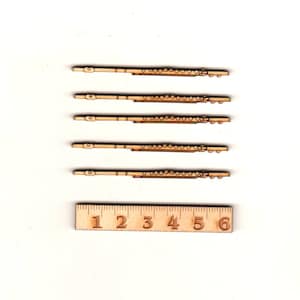 Può includere: Cinque sagome di flauto in legno, ciascuna misura circa 15 cm di lunghezza, disposte verticalmente su uno sfondo bianco. Un righello di legno con i numeri da 1 a 6 è posizionato sotto le sagome.
