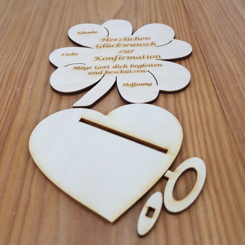Op de afbeelding: Houten klavertje vier kaart met de tekst "Herzlichen Gl&uuml;ckwunsch zur Konfirmation M&ouml;ge Gott dich begleiten und besch&uuml;tzen. Hoffnung" en een houten hart met een sleutel.