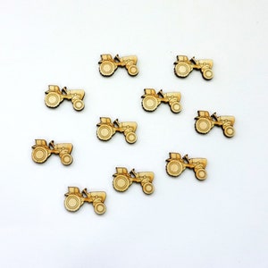 Könnte beinhalten: Zehn hölzerne Traktor-Ausschnitte in hellbrauner Farbe. Die Traktoren sind alle in die gleiche Richtung ausgerichtet und in einem Halbkreis auf weißem Hintergrund angeordnet.